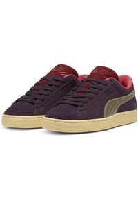 Tamno ljubičaste suede tenisice s bež potplatom, bordo naglascima na jeziku i unutrašnjosti, te zlatnim Puma logom sa strane.