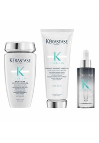 Das Kérastase Symbiose Haarpflege-Set umfasst ein weißes Shampoo im Tiegel mit silbernen Akzenten, einen weißen Conditioner in der Tube und ein klares Serum mit Tropfer.