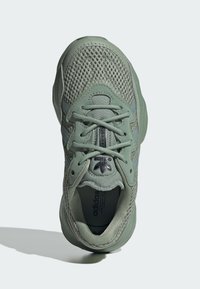 Light green athletic shoe with a mesh upper, round toe, and lacing system. Features textured accents and a padded collar for comfort.