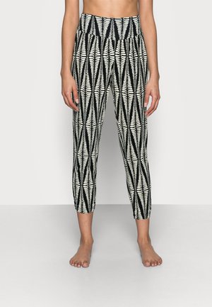 Black and white patterned leggings with a high waistband, featuring a leaf design and fitted ankles, made from a stretchy material.