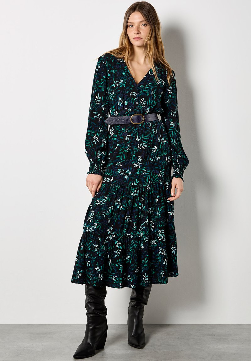 Schwarzes Blumen Kleid mit grünen und blauen Blattmustern, verfügt über einen gestuften Rock, lange Ärmel, V-Ausschnitt und ist mit einem Gürtel in der Taille gerafft.