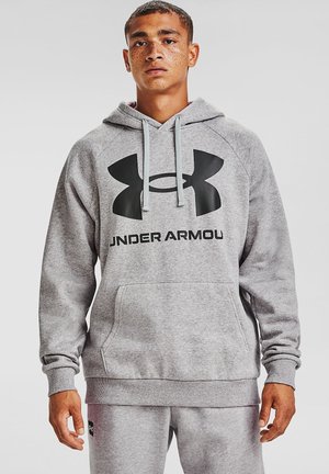 Sudadera con capucha gris hecha de una tela suave, con un bolsillo canguro, que presenta un gran logo negro de Under Armour en el pecho y cordones en contraste.