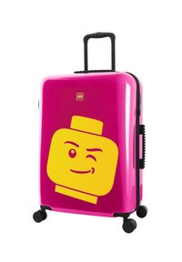 Hard-shell suitcase with vibrant pink exterior featuring a large yellow LEGO head graphic. Black retractable handle and wheels included.