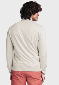 Helles beige Langarmhemd mit glatter Textur, schlanker Passform und hohem Kragen, kombiniert mit korallenfarbenen Shorts. Einfaches Design ohne Muster.