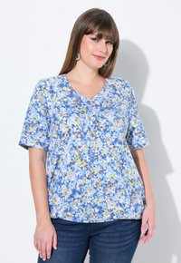 Camiseta floral con escote en V, que presenta patrones de color azul, amarillo y marrón. Manga corta, corte relajado, fabricada con tejido ligero.