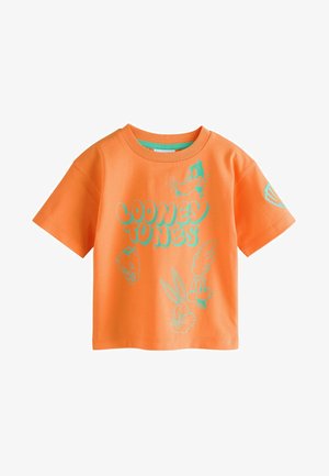Oranssi puuvillapaita lyhyillä hihoilla, jossa on teal-värisiä Looney Tunes -hahmoja painettuna etupuolelle ja logo hihassa.
