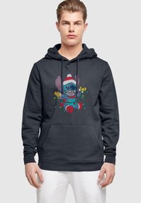 Felpa grigia scura con un personaggio cartoon colorato che indossa un cappello di Babbo Natale, mentre tiene delle stringhe di luci natalizie e presenta una tasca a marsupio frontale.