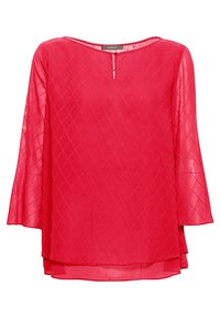 Blouse rouge à manches longues avec motif matelassé en losanges, encolure ronde avec une petite ouverture devant et un ourlet superposé.