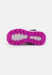 Talpa de pantof sport negru cu o talpă intermediară albă și un model de tracțiune de un roz strălucitor. Prezintă nubs rotunde și caneluri în zigzag pentru aderență.
