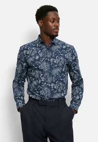 Navy Paisley-Muster-Hemd aus Baumwollstoff mit klassischem Kragen und langen Ärmeln, kombiniert mit dunklen Anzughosen.