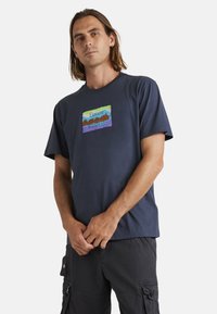 Marineblauwe katoenen t-shirt met een veelkleurige rechthoekige graphic met de tekst "Element Skateboard Co Worldwide". Korte mouwen en een ronde hals.