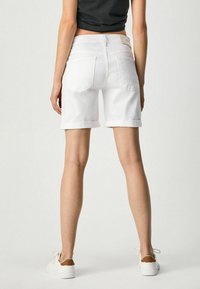 Shorts in denim bianco con orli arrotolati, cinque tasche e etichetta in pelle sulla vita posteriore. Tessuto morbido, design a vita media.