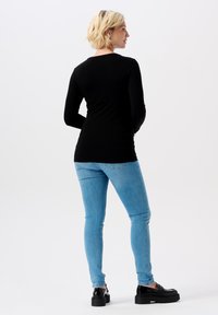 Svart långärmad topp som matchas med ljusblå slim fit-jeans och svarta platåskor. Slät tyg med en figurnära design och rundad halsringning.