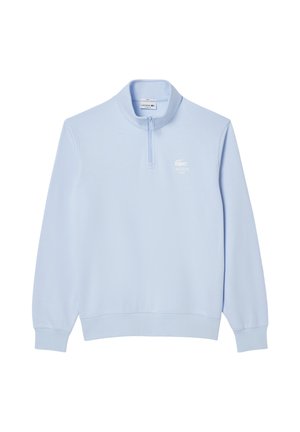 Jasnoniebieska bluza zip-up z wysokim kołnierzem, wykonana z miękkiego materiału. Posiada białe logo Lacoste na lewej piersi. Długie rękawy.