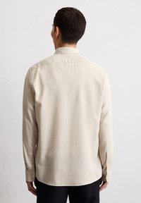Beige Langarmhemd aus glattem Stoff mit einem Button-down-Kragen und geknöpften Manschetten, mit einem geraden Saum hinten.