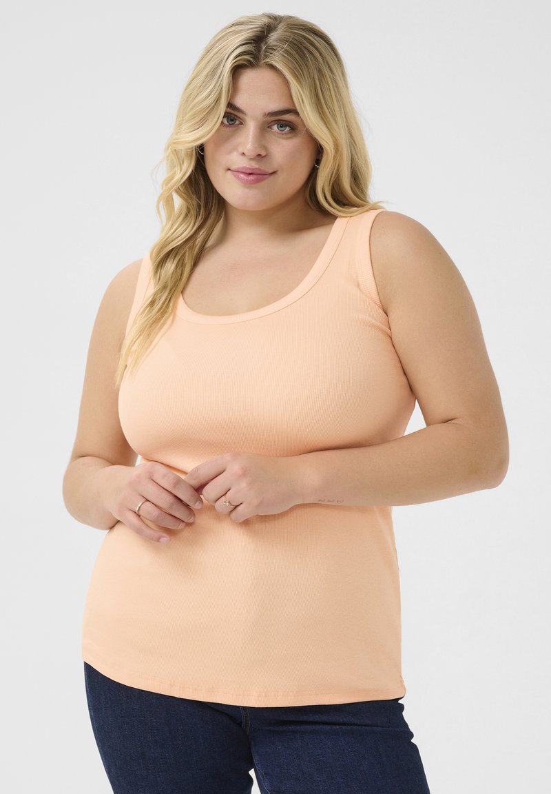Peach ribbed tank top with a scoop neckline, fitted design, and a straight hem, paired with dark blue jeans.