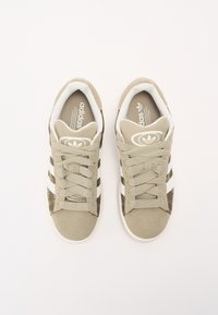 Béžové sportovní boty ze semiše a síťoviny, s bílými pruhy, zaoblenou špičkou a texturovaným svrchním dílem s logem.