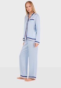 Light blue pajama set features a patterned top with a pocket, navy trim, and matching pants with contrasting stripes at the hem.