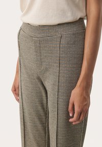 Kalhoty s pracovním vzorem houndstooth v hnědé, béžové a černé barvě. Hladká textura, vysoký pas a přiléhavý střih s bočními kapsami.