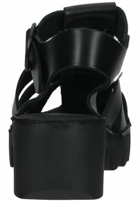 Černé platformové sandály se silnou patou, vybavené zakřivenými popruhy a detailem přezky, vyrobené z hladkého syntetického materiálu.