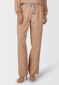 Beige wide-leg trousers with an elastic waistband and gray drawstring. Features two front pockets and a smooth texture.