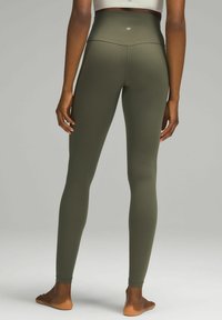 Hochtaillierte olivgrüne Leggings aus dehnbarem Material, mit einer glatten Textur und einem Logo-Akzent am hinteren Taillenbund.