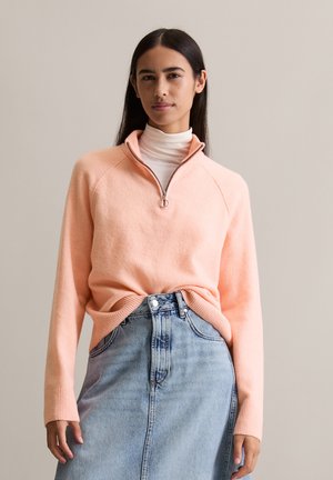 Lichtroze pullover met een ritskraag, ribgebreide manchetten en een relaxte pasvorm, gecombineerd met een spijkerrok. Glad textuur, casual ontwerp.