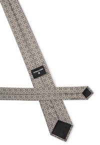 Tirettes à motifs beige et gris avec des designs géométriques ; dotées d'un onglet en cuir noir et d'un patch logo. Fabriquées en tissu tissé.