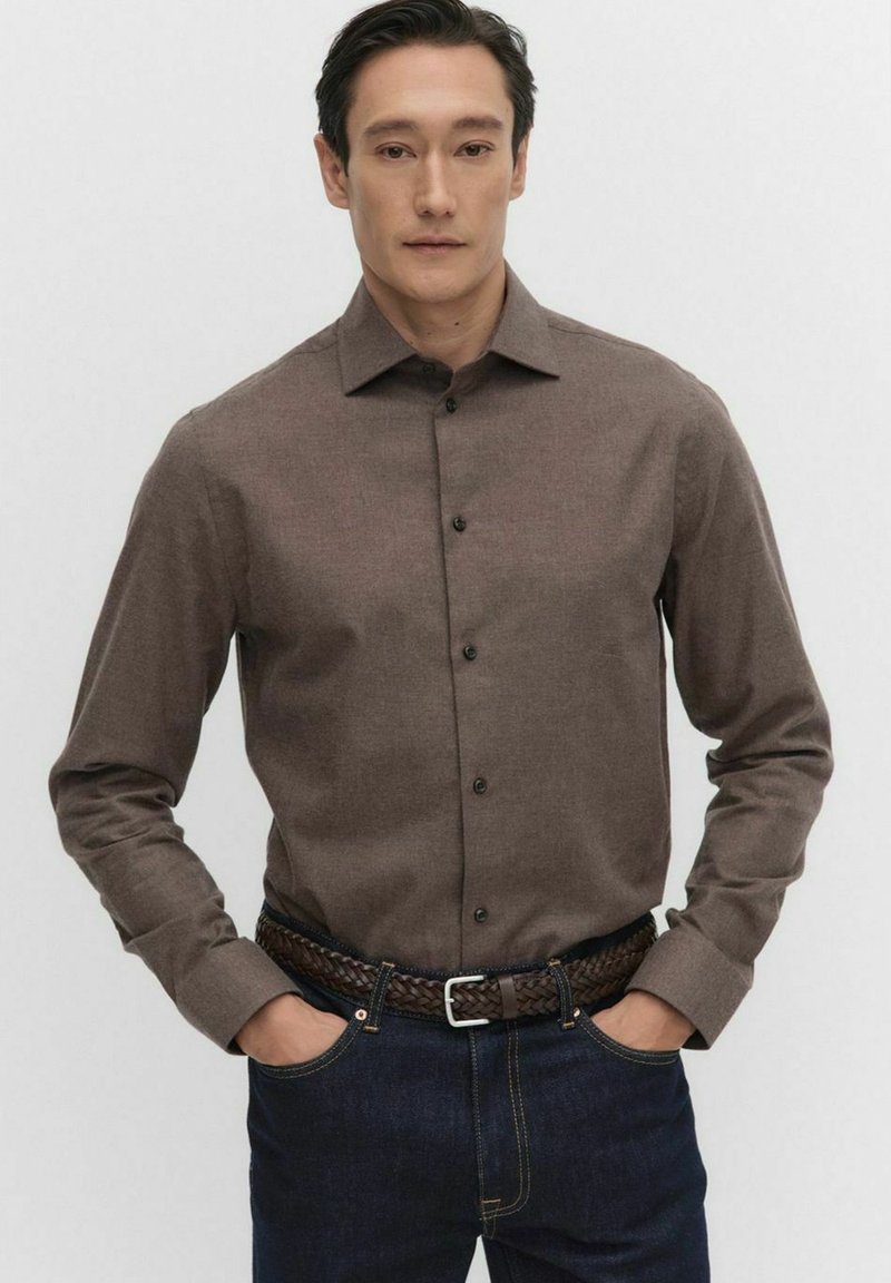Brun långärmad skjorta med knäppning och texturerad tyg. Kombination med mörka denimjeans och ett flätat bälte.