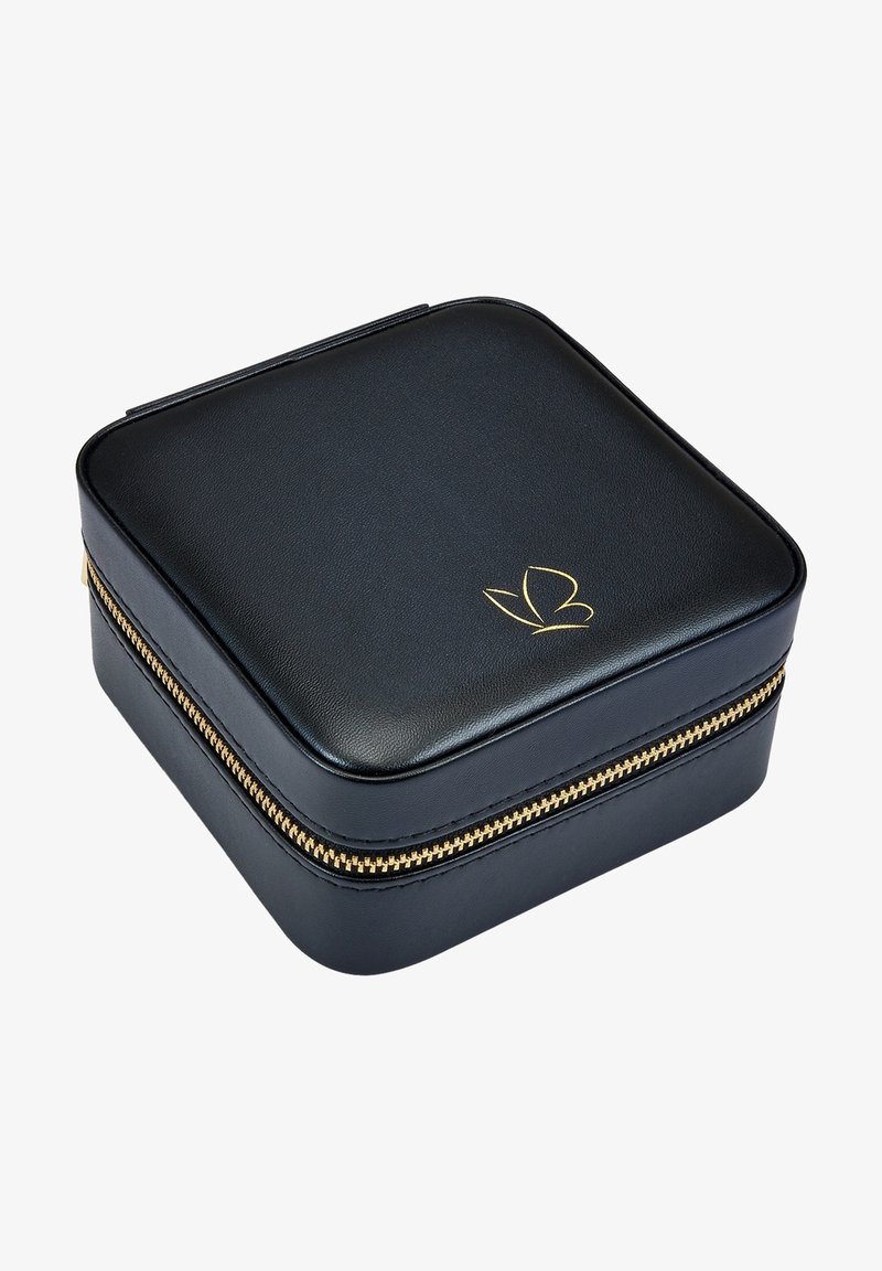 Black leather travel jewelry case with a gold zipper, square shape, slightly rounded edges, and a gold logo on the top.