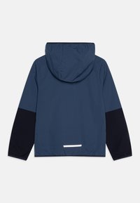 Veste à capuche bleu marine avec des manches noires contrastantes, des poignets élastiques et une bande réfléchissante blanche à la taille. Fabriquée en tissu léger et lisse.