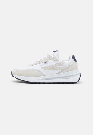 Sneakers in pelle bianca e suede beige con un accento blu scuro sul tallone e una suola in gomma ammortizzata, dotati di allacciatura standard.