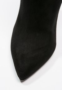 Czarny skórzany but na wysokim obcasie z ostrym noskiem i gładką fakturą, charakteryzujący się eleganckim, minimalistycznym designem. Brak widocznych elementów metalowych lub wzorów.