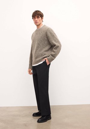 Hallhärm, millel on tekstuuriga hall kangas ja ümar kaelus, on kombineeritud mustade laia lõikega pükstega ning mustade sidumiskingadega.