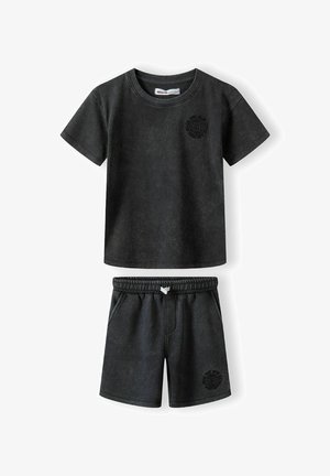 Crni pamučni šorts i majica s kratkim rukavima, elastičnom gumicom u struku, bočnim džepovima i okruglim grafičkim printom na prsima i šortsu.