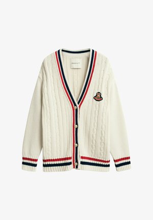 Cardigan in maglia a catena color crema con rifiniture a strisce rosse, blu navy e bianche, chiusura con bottoni e stemma ricamato sul petto.
