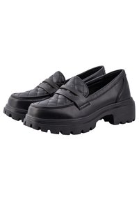 Mocassins en cuir noir avec un motif matelassé sur le dessus, des semelles épaisses à crampons, et une bande décorative sur le devant.