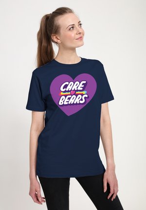 Marineblauwe T-shirt met een paarse hartontwerp en de tekst "CARE BEARS" in wit, geel en rood, gemaakt van katoen met een gladde textuur.