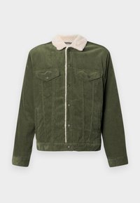 Casaco de veludo cotelê verde com um colarinho de fleece creme, apresentando dois bolsos no peito, botões de pressão e uma superfície texturizada.