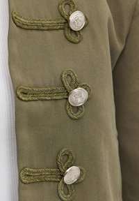 Veste vert olive avec trois boutons en argent ornés et des fermetures à boucles tressées en fil doré et vert.
