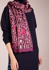 Écharpe à imprimé léopard dans des nuances de bordeaux et rose, ornée de grandes lettres graphiques, en tissu doux, à la texture lisse.