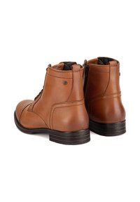 Hnedé kožené členkové topánky s hladkým povrchom, zaoblenou špičkou, šnurovaním vpredu a bočným zipsom. Pevná čierna gumová podrážka s jemnými štepovými detailmi.