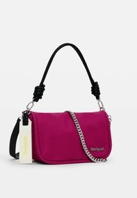 Borsa a tracolla rosa in nylon con tracolla in pelle nera, catena argento e etichetta bianca con il nome del marchio "Desigual" in giallo.