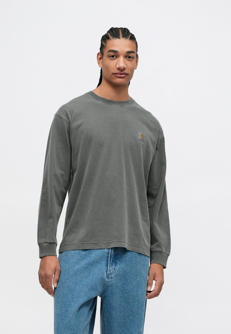 Grijze katoenen T-shirt met lange mouwen en een ronde halslijn, voorzien van een klein logo op de borst, gecombineerd met blauwe spijkerbroek.