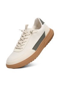 Witte canvas sneaker met een groene streep, textuurelement en lichtbruine rubberen zool. Heeft platte veters en een gewatteerde kraag.