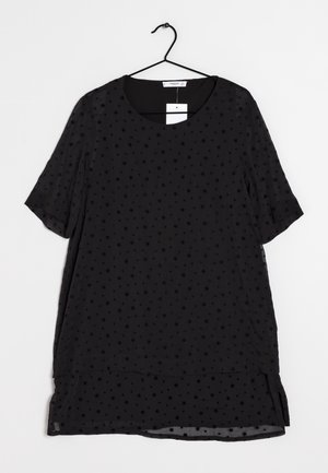 Robe noire à manches courtes avec de petits motifs d'étoiles suspendue sur un cintre noir sur fond blanc.