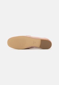 Light pink suede shoe with a rounded toe and a flexible tan rubber outsole featuring horizontal grooves for grip.