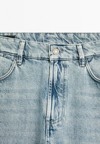 Light blue denim jeans featuring a classic five-pocket design, silver button closure, and a slightly faded texture.