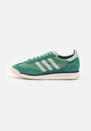 Zielony but sportowy Adidas SL 72 z białymi paskami, beżową podeszwą i zamszowymi akcentami, pokazany z profilu na białym tle.