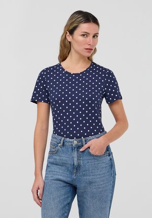 T-shirt navy con pois bianchi, maniche corte, scollatura tonda, realizzata in cotone, abbinata a jeans in denim azzurro chiaro a vita alta.